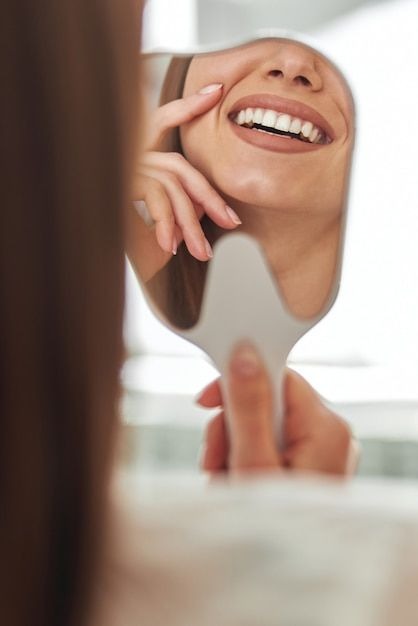Patient looking at her perfect smile in a hand mirror